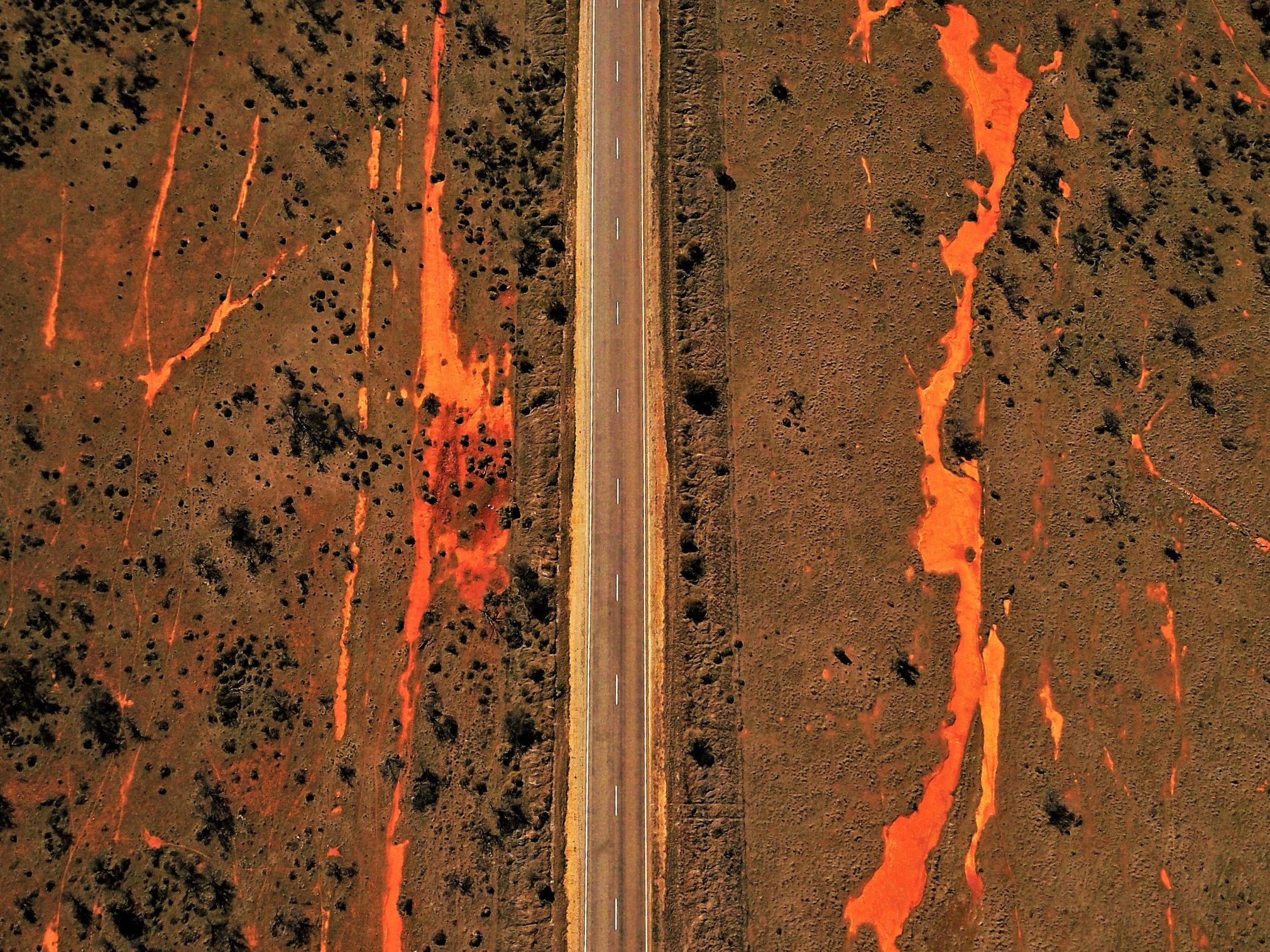 Overhead photograph of a road bisecting an outback landscape.